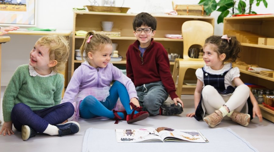 four students sitting on the floor reading together