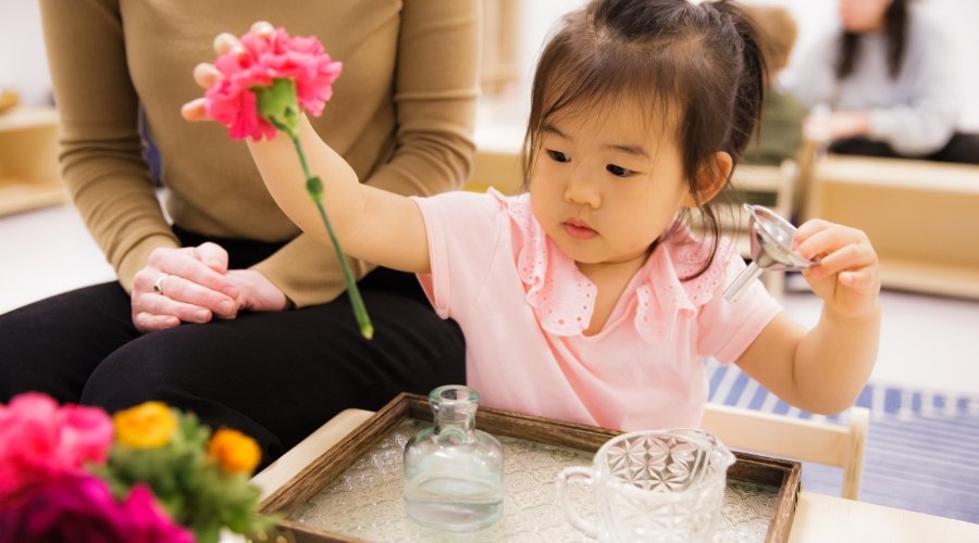 Toddler student putting artificial flower in a vase